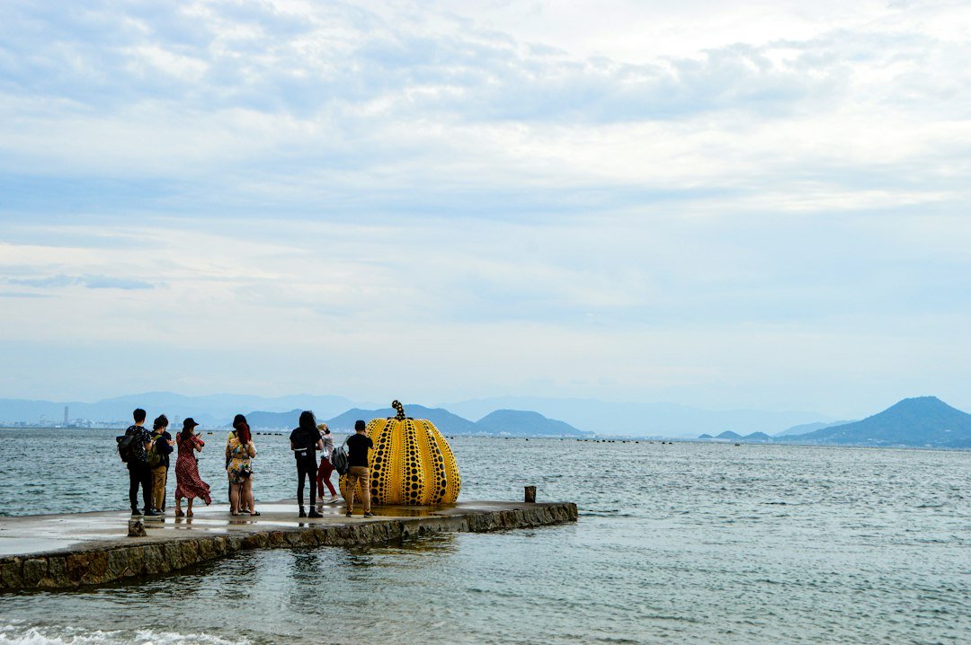 Naoshima adasında sarı kabak heykelinin önünde fotoğraf çeken turistler