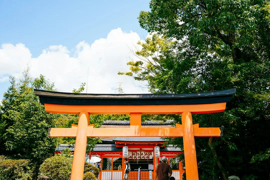 Uji'de yeşilliklerin arasında turuncu bir Şinto tapınağı torii kapısı