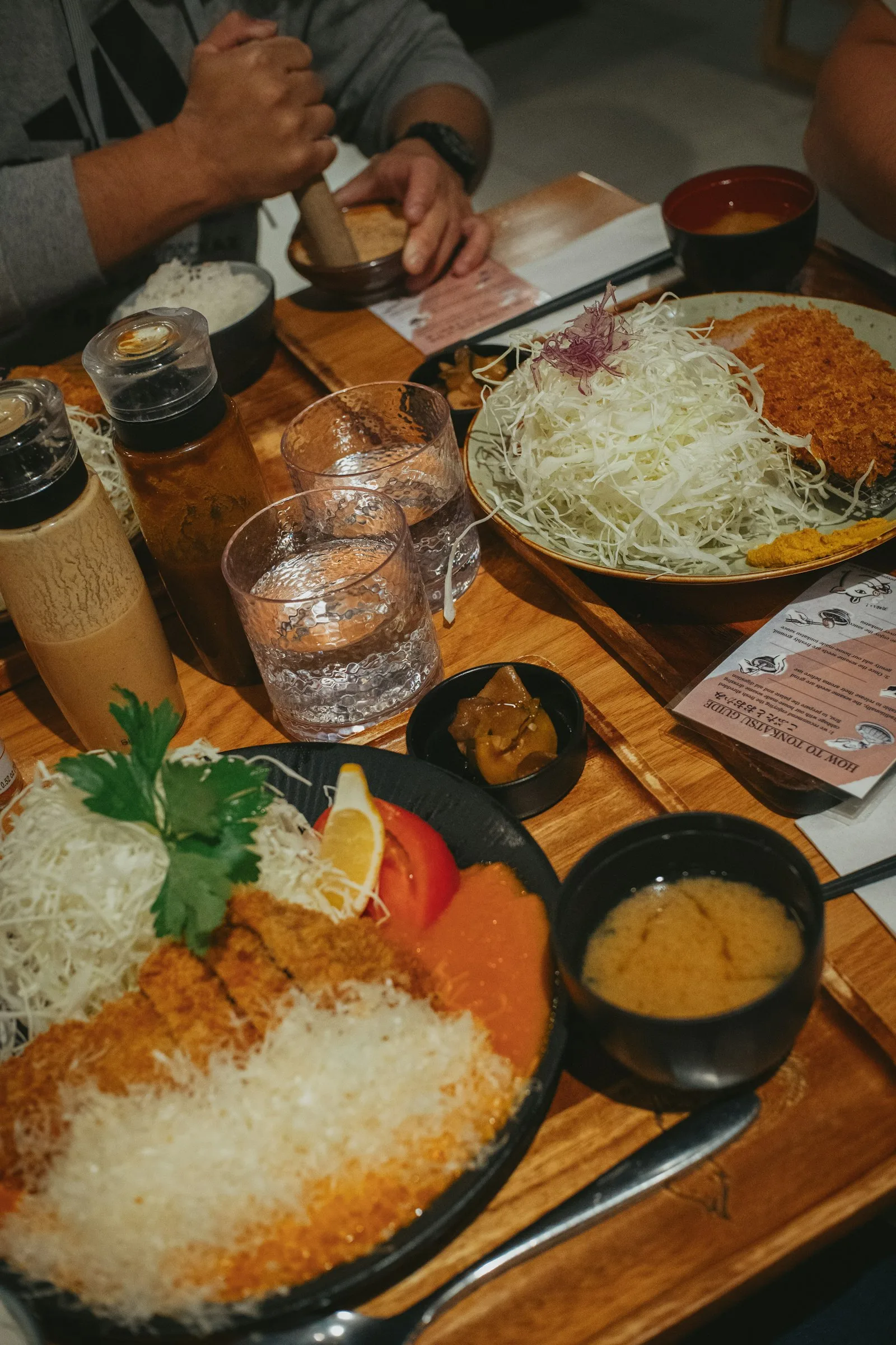 Ahşap masada tonkatsu seti: lahana, katsu, pirinç, miso çorbası ve susam öğüten kap
