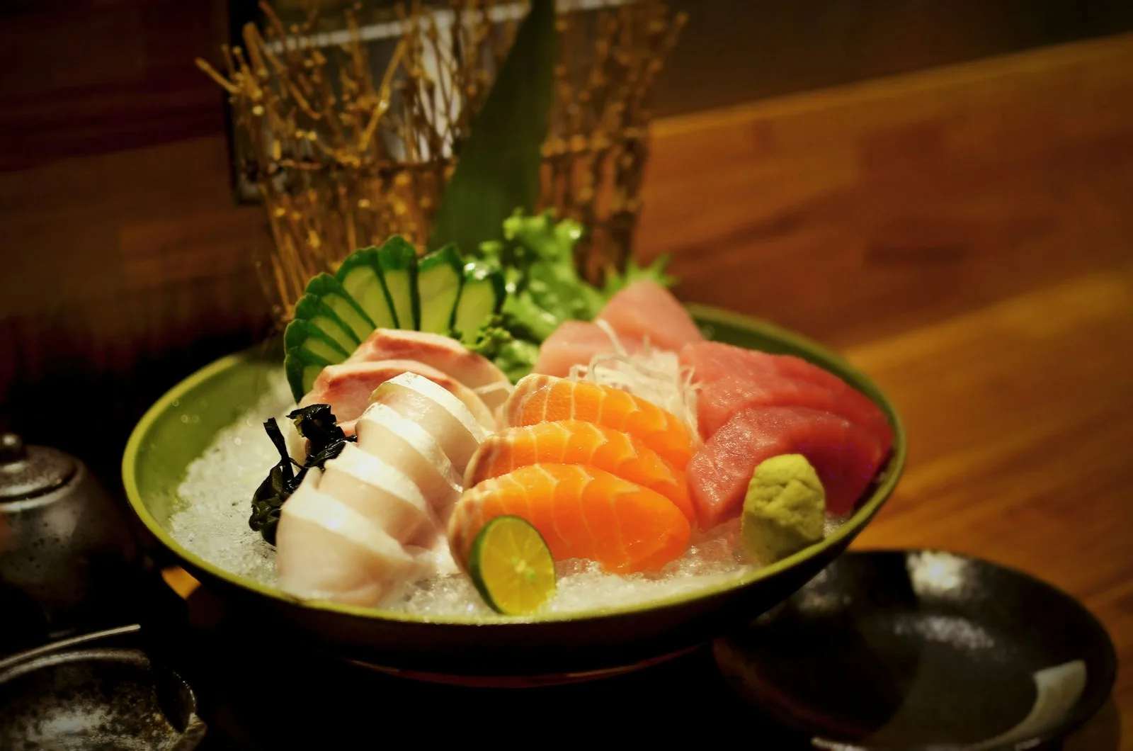 Buz üzerinde somon, ton balığı ve beyaz balık dilimlerinden oluşan sashimi tabağı, yanında wasabi ve limon
