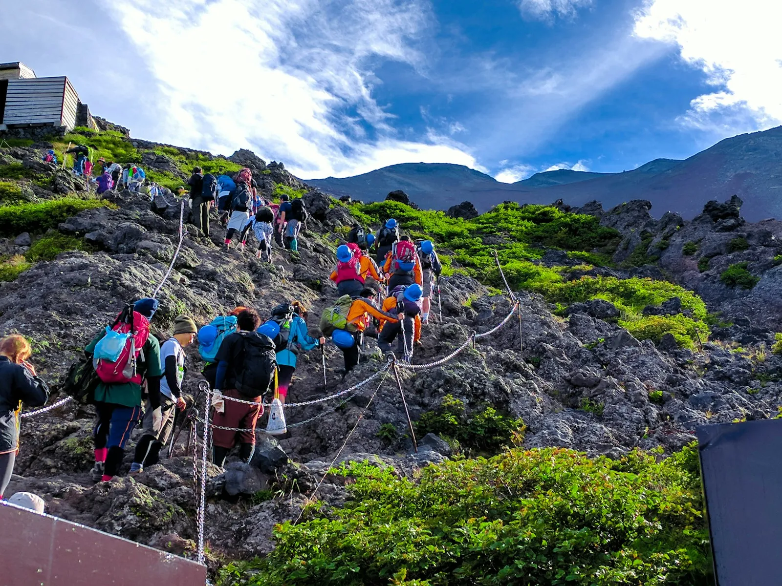 Fuji Dağı'nda kayalık patikada sıra hâlinde tırmanan insanlar