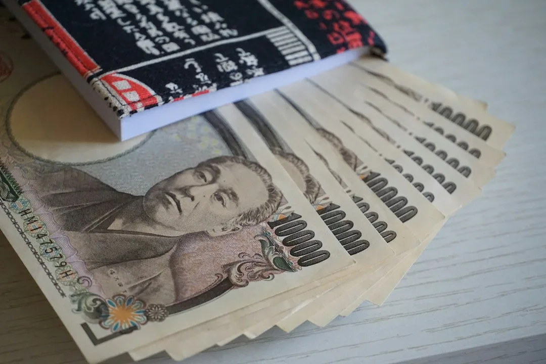 Japonca desenli bir cüzdanın yanında yelpaze gibi açılmış 10.000 yenlik banknotlar
