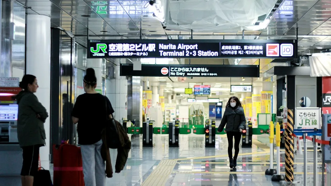 Narita Havalimanı tren istasyonu girişinde valizleriyle yürüyen yolcular