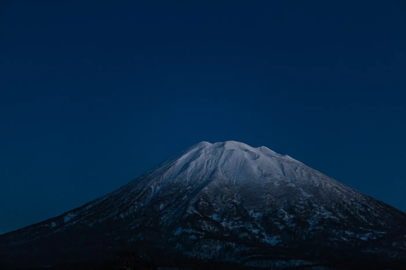 Gece mavisi gökyüzünde Yotei Dağı siluet
