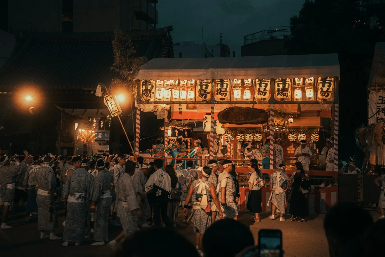 Gece ışıkları altında tapınak önündeki festival kalabalığı