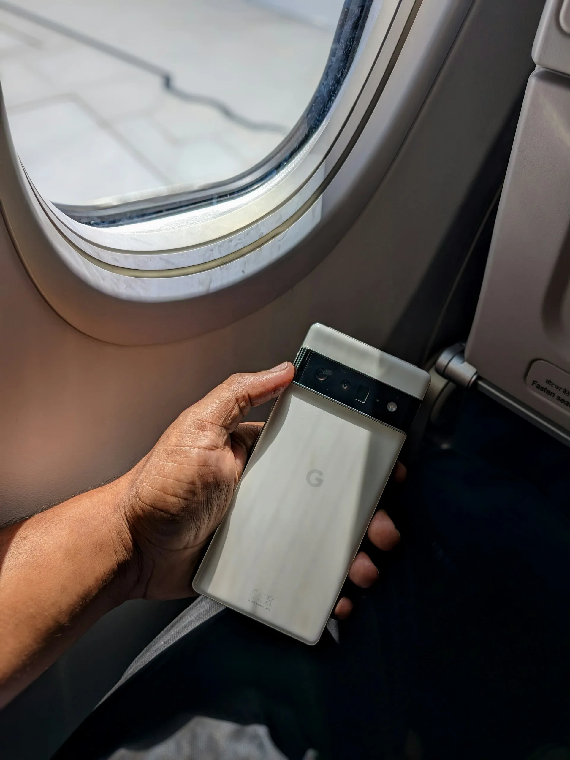 Uçak penceresinin yanında telefon tutan bir yolcu